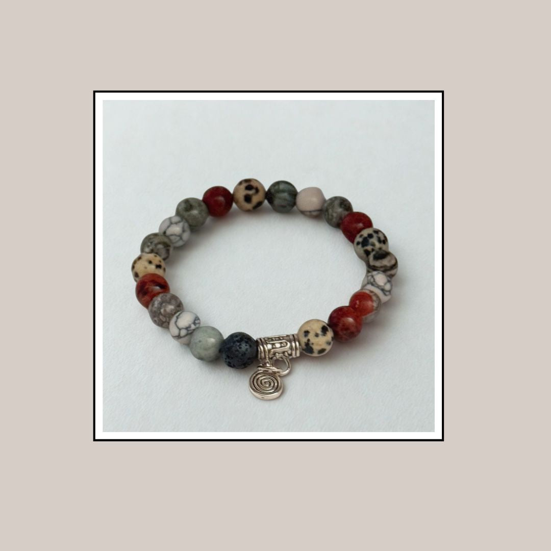 Multicolored beaded bracelet with a silver charm on a light gray background