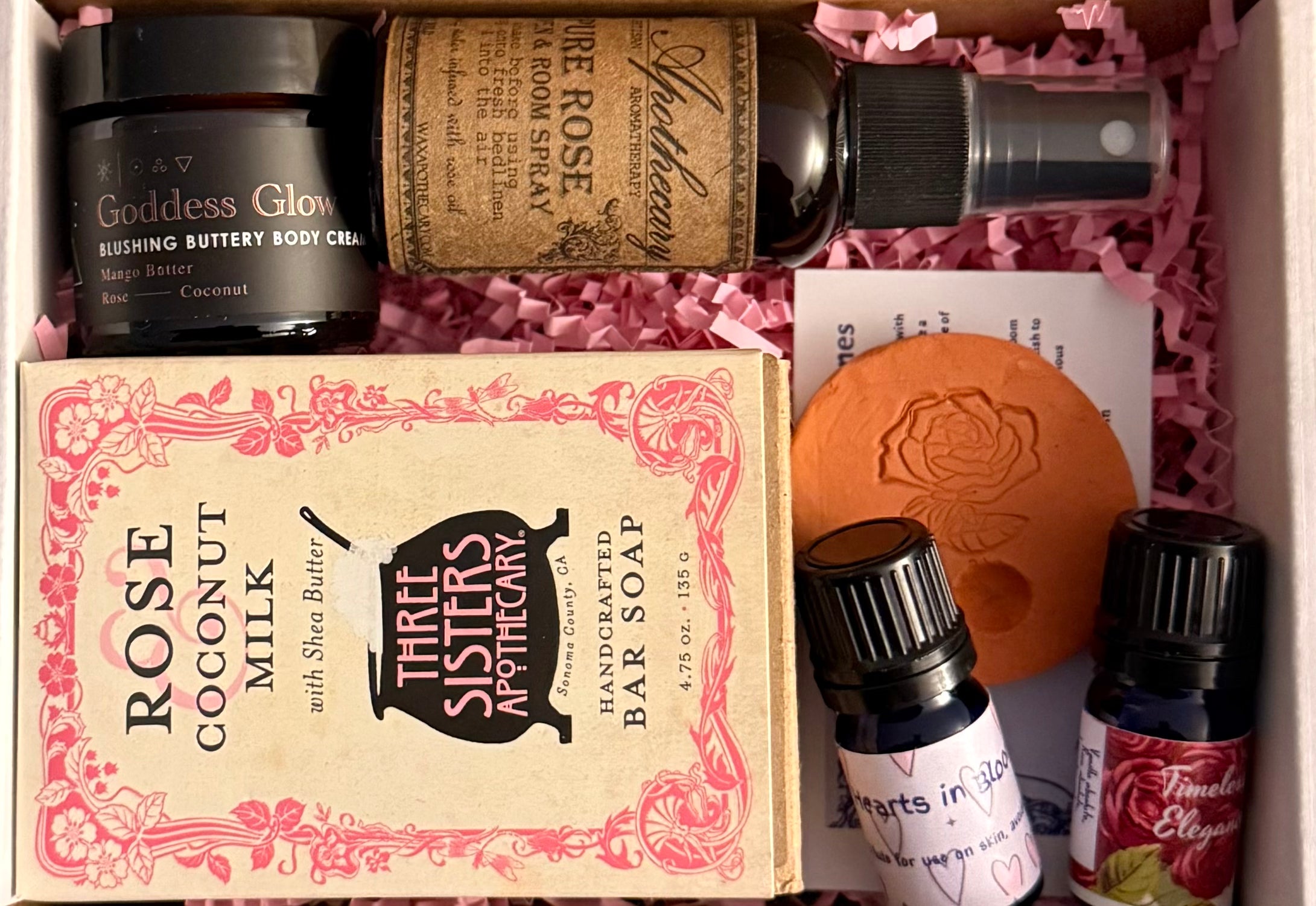 Collection of beauty products including a bar of soap, body care items, and essential oils in a box.