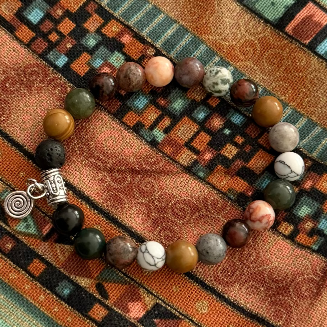 gemstone bracelet with a silver spiral charm on a patterned fabric background